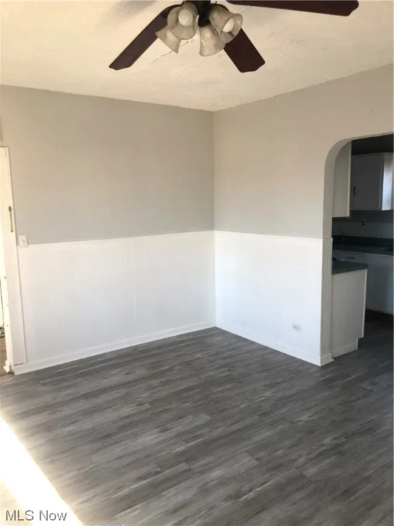 Unfurnished room with dark hardwood / wood-style floors, ceiling fan, and a textured ceiling