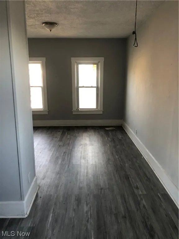 Spare room with dark wood-type flooring and a textured ceiling