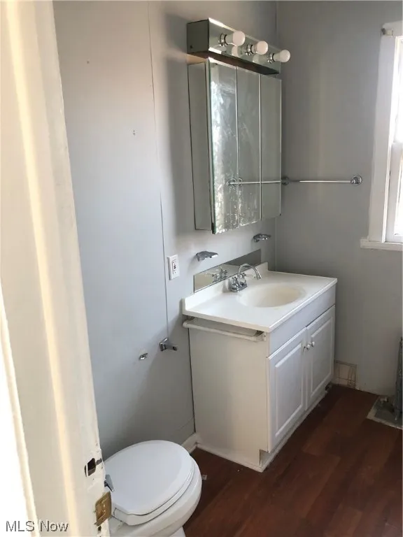 Bathroom with toilet, vanity, and hardwood / wood-style floors