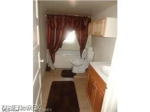 Full bathroom featuring tile flooring, vanity, toilet, and shower / bath combo with shower curtain