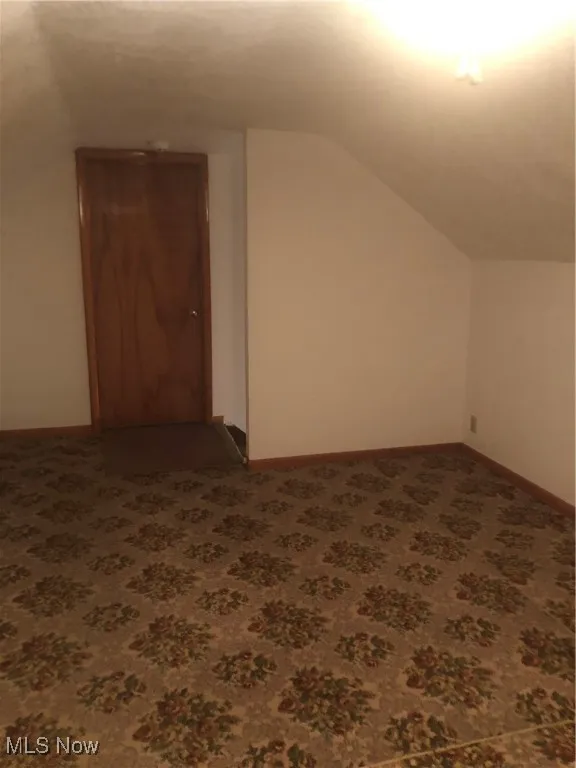 Bonus room featuring lofted ceiling, carpet floors, and baseboards