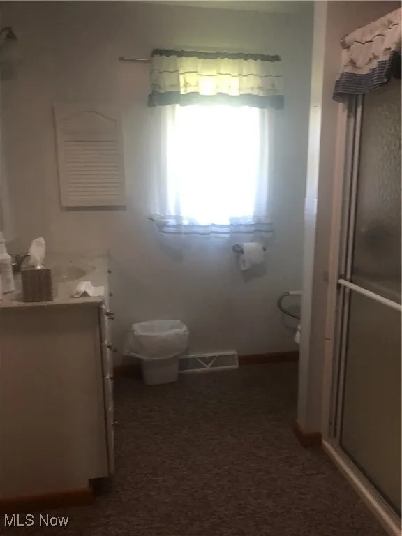 Full bathroom featuring a stall shower, vanity, visible vents, and baseboards