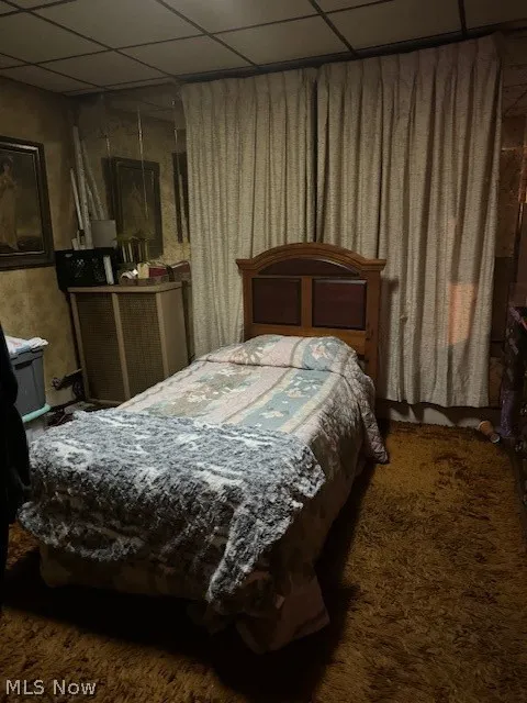 Carpeted bedroom featuring a drop ceiling
