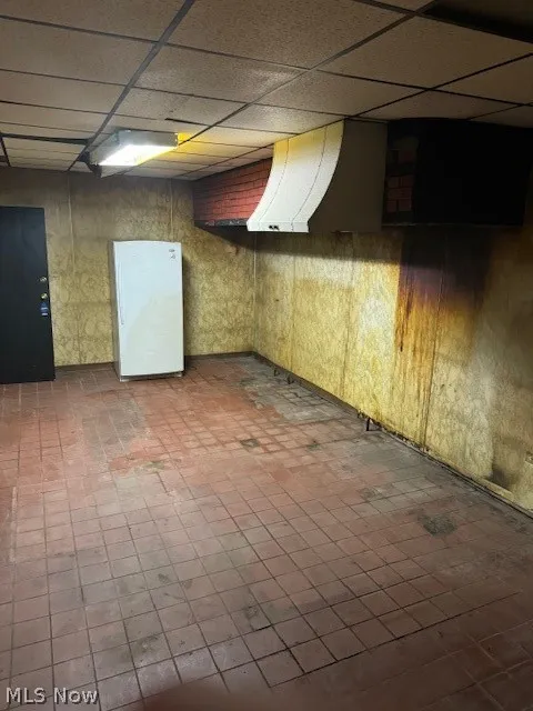 Basement with tile flooring and a paneled ceiling