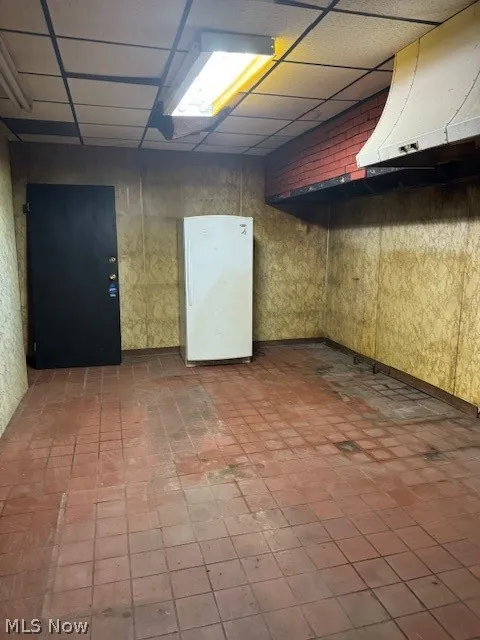 Basement with a drop ceiling and tile flooring