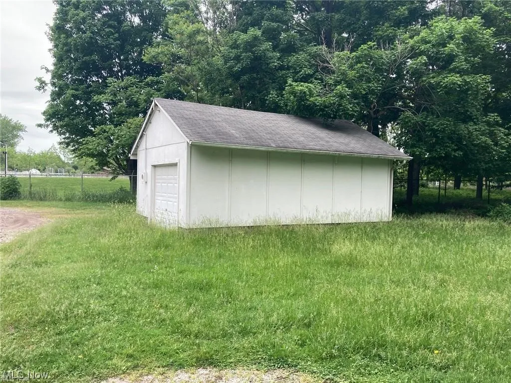 View of outdoor structure featuring a lawn and a garage