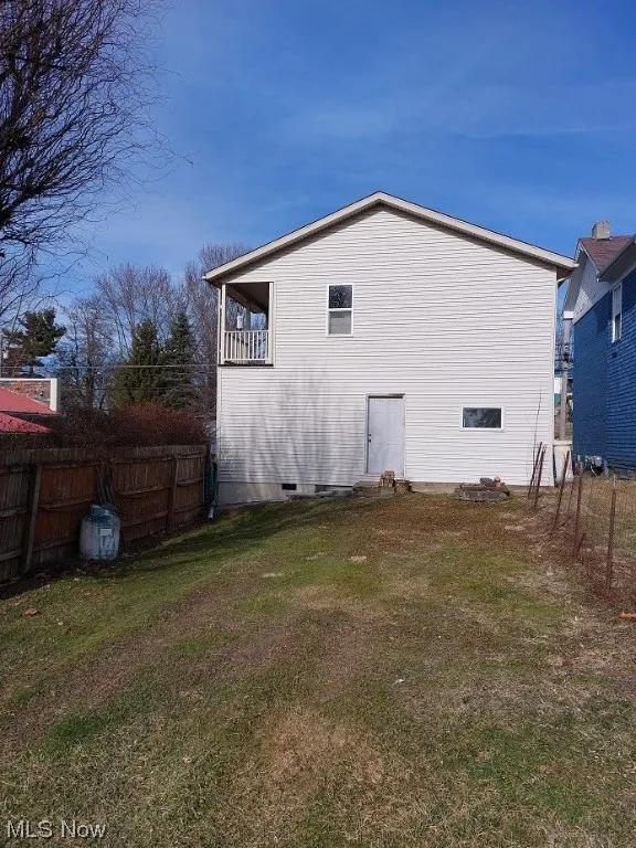 View of side of property with a lawn and a balcony