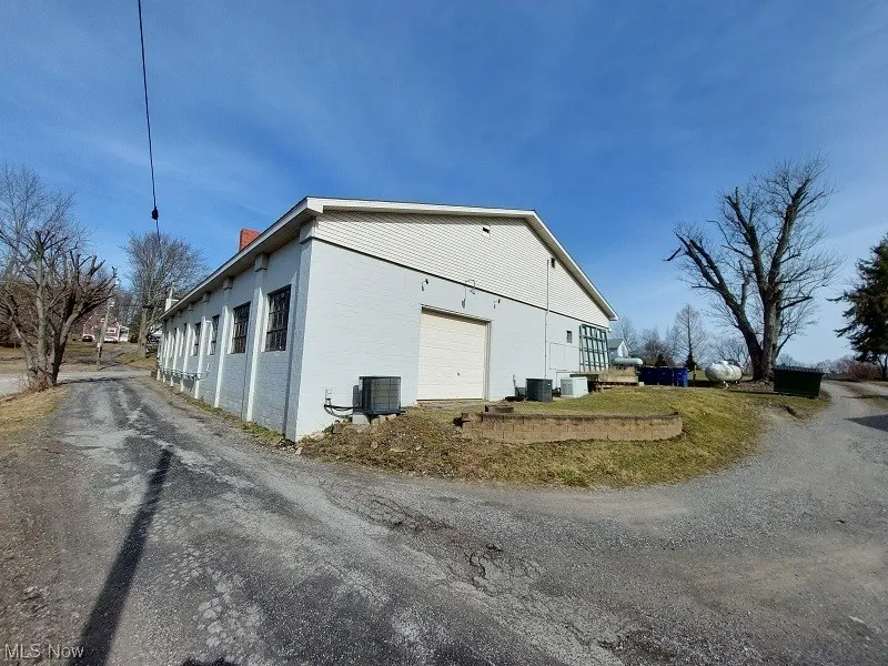 View of home's exterior featuring a lawn, a garage, and central air condition unit
