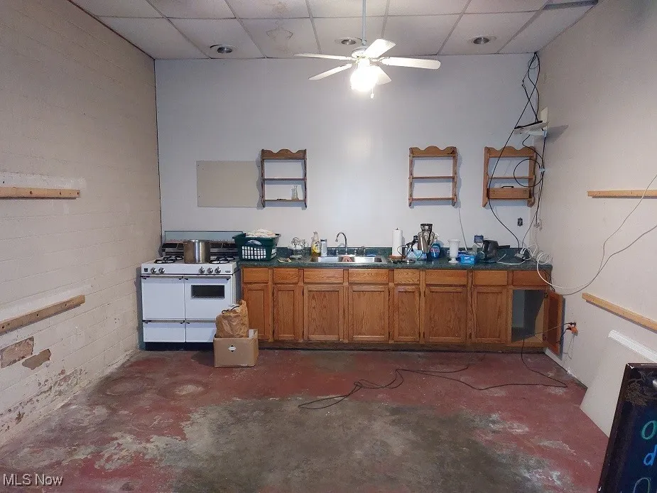 Kitchen with white range with gas stovetop, a paneled ceiling, ceiling fan, and sink
