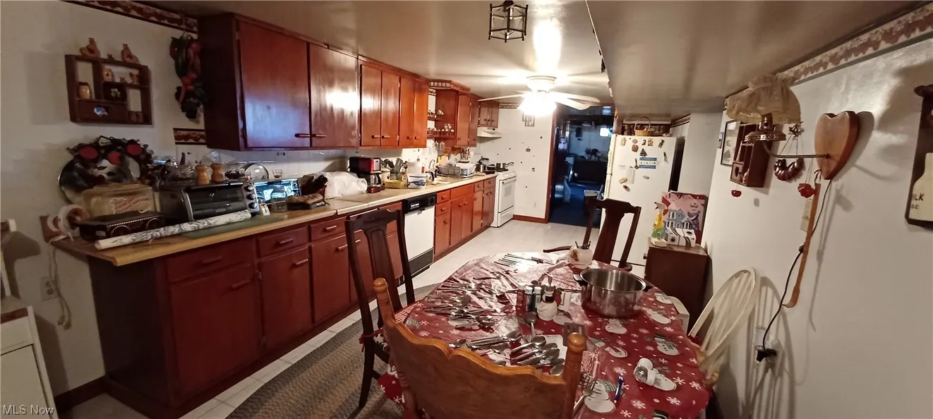 Lower level Kitchen featuring white appliances, ceiling fan, and light ceramic tile floors