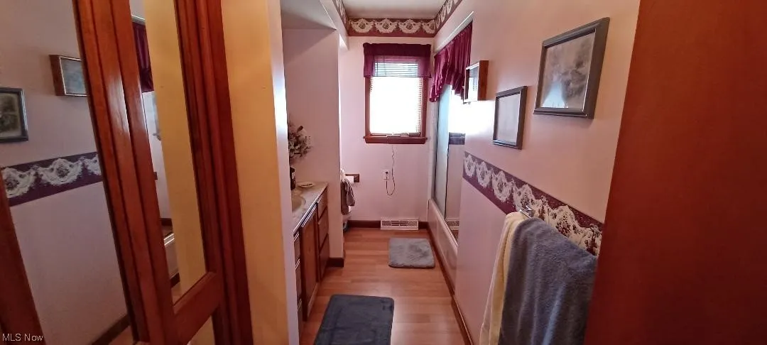 Main floor bath featuring light laminate/ wood-style floors