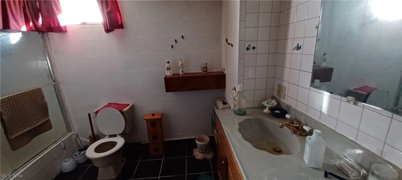 Lower level Bathroom featuring tile walls, tile floors, backsplash, and toilet