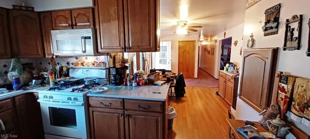 1st floor Kitchen with white appliances, light laminate / wood-style floors, and ceiling fan