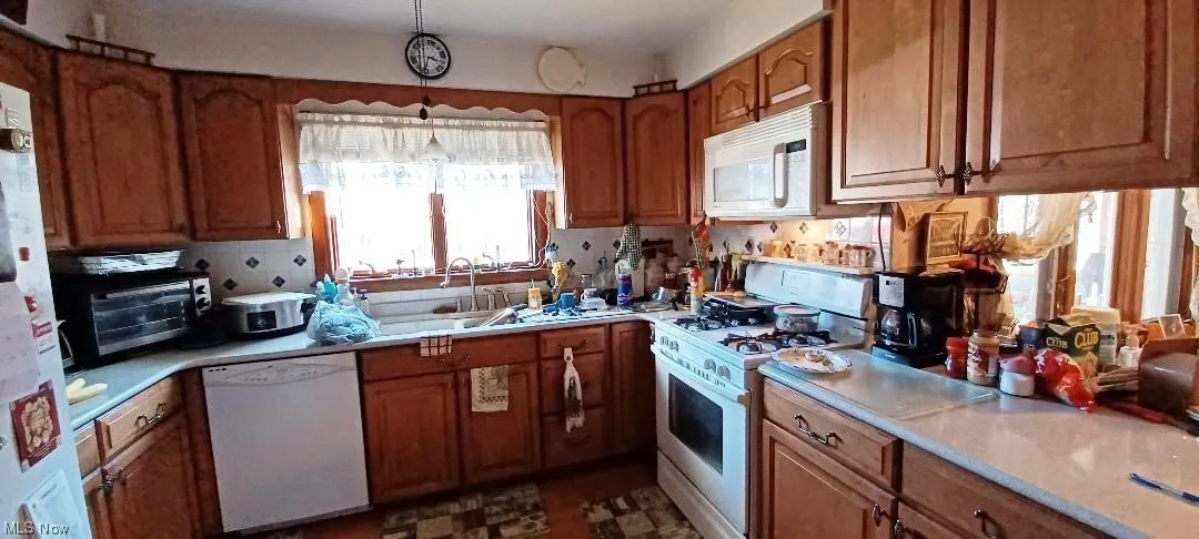 First floor Kitchen featuring white appliances, sink, pendant lighting, and tasteful backsplash