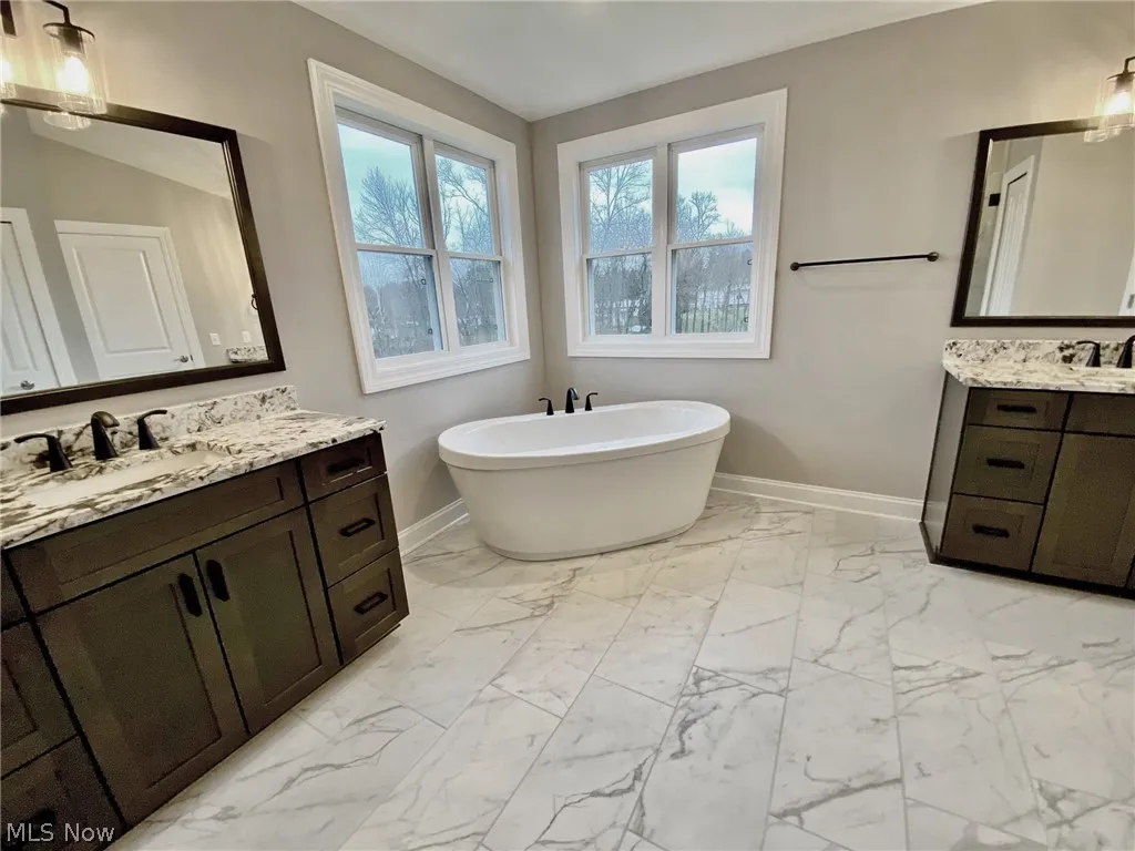 Bathroom featuring tile flooring, a stand alone tub and separate vanites