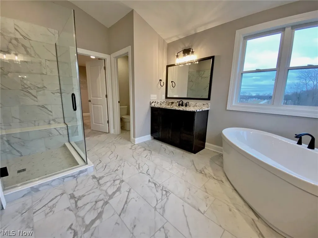 featuring tile flooring, shower with separate bathtub, toilet, and separate vanities