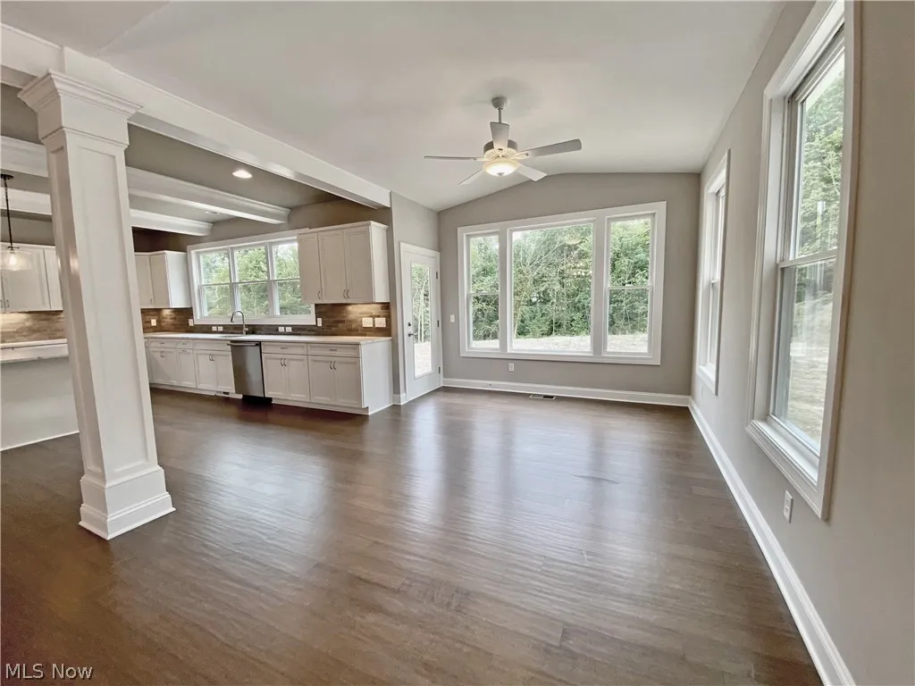 Sunroom featuring vaulted ceiling, ceiling fan, ornate columns, and hardwood flooring