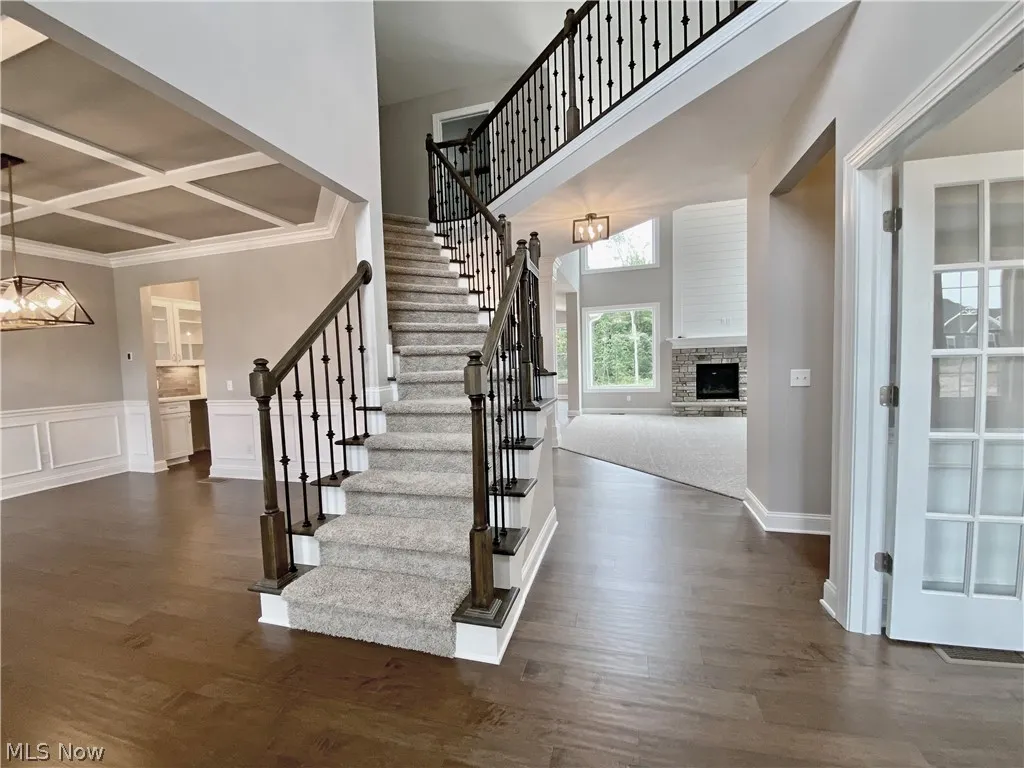 Stairs with Hardwood floors, a chandelier, coffered ceiling, ornamental molding, and a high ceiling