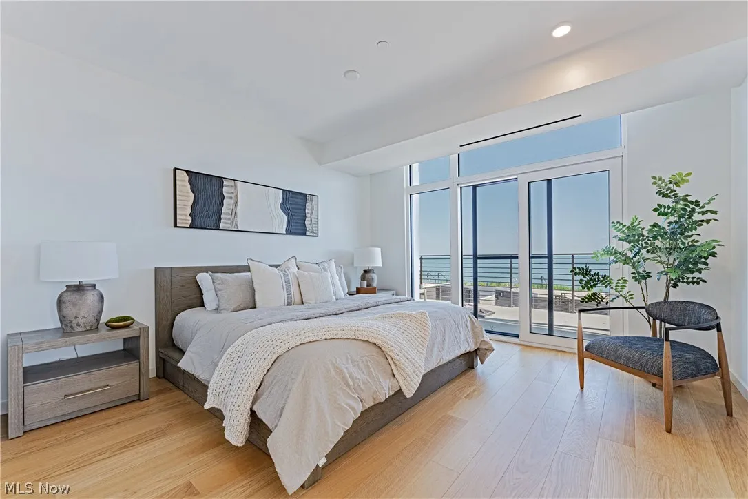 Bedroom featuring a water view, light wood-type flooring, and access to outside