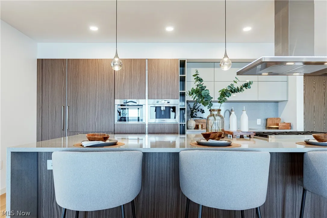 Kitchen with island exhaust hood, white cabinets, tasteful backsplash, and a breakfast bar