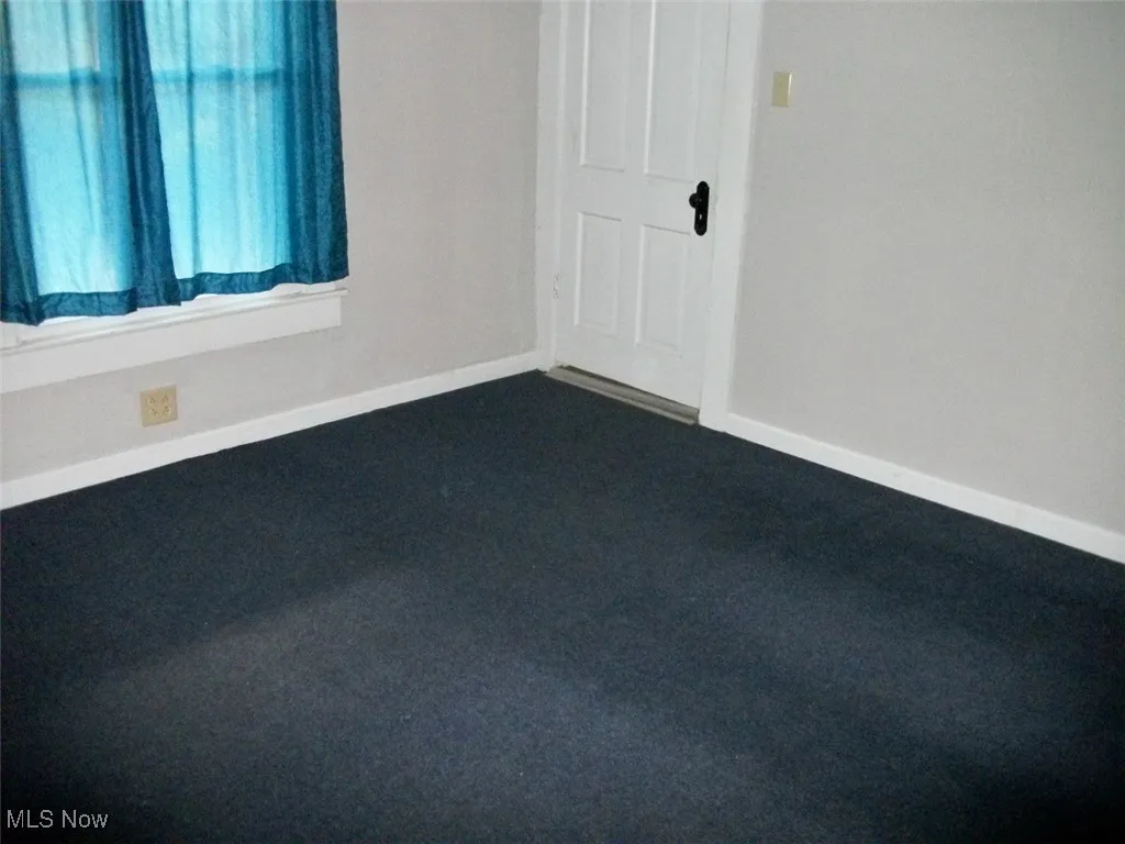 Bonus room with dark colored carpet and baseboards