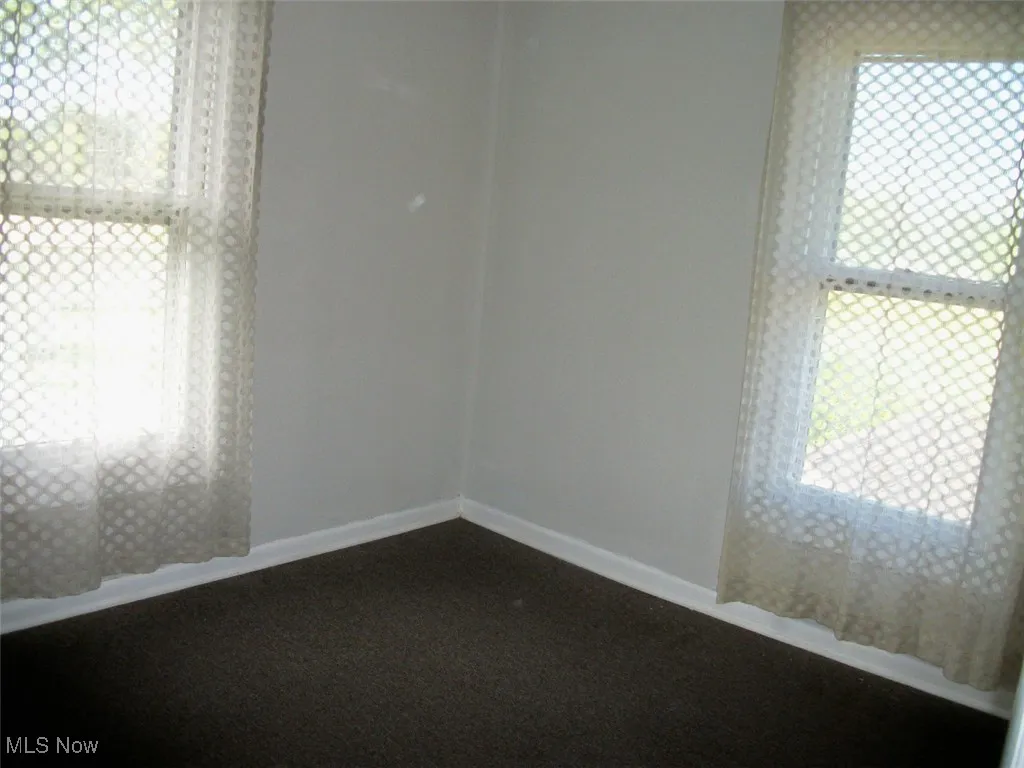 bedroom room featuring baseboards, dark colored carpet, and plenty of natural light