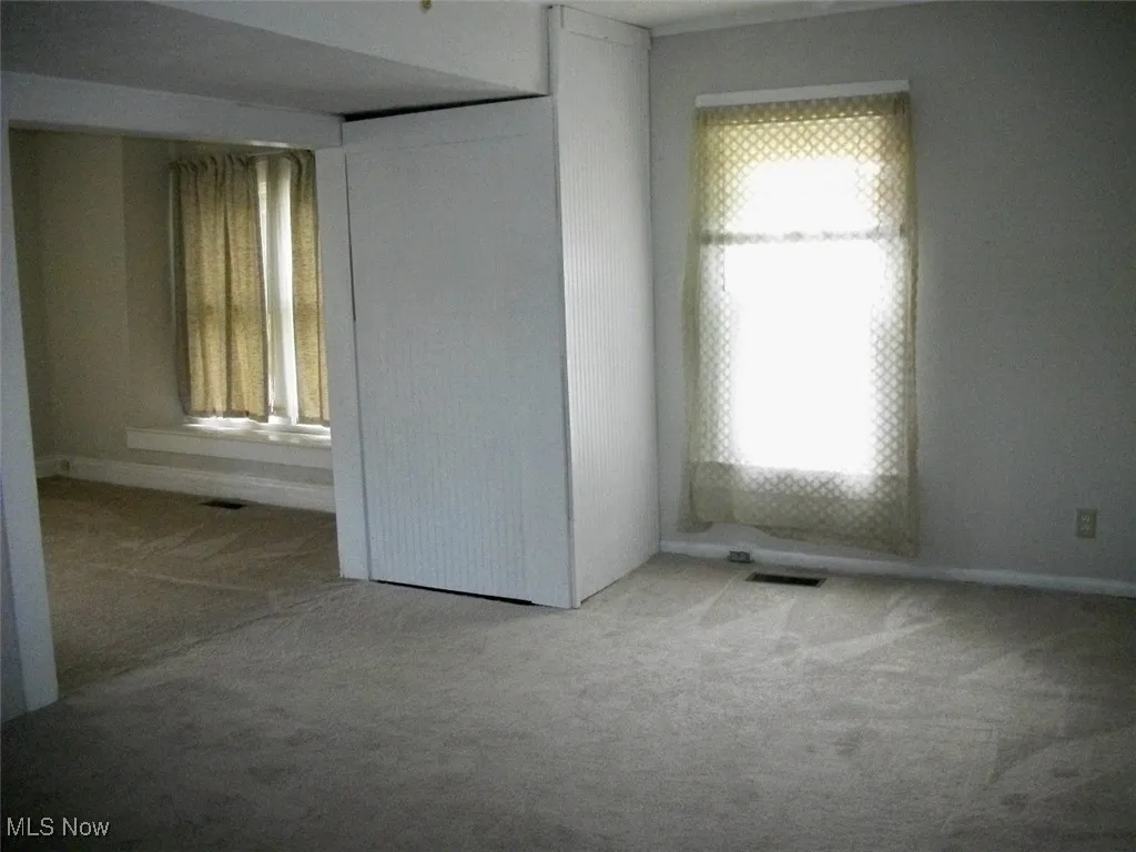 living room leading to dining area with neutral carpet.