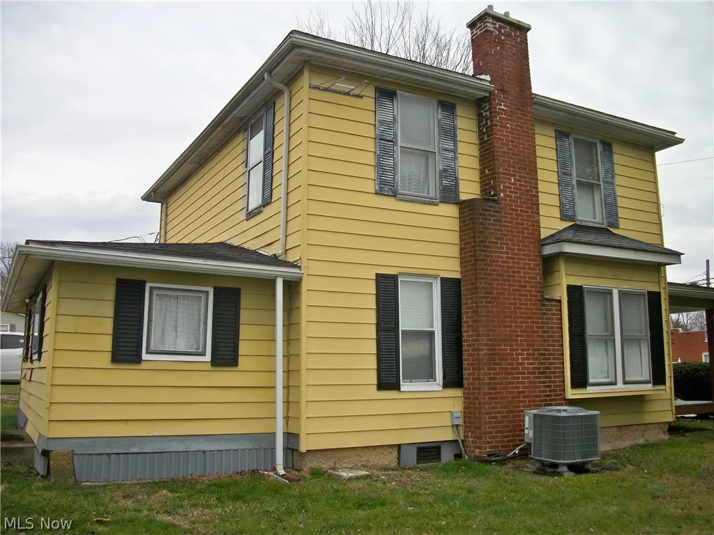  side view of property featuring central AC unit and a yard