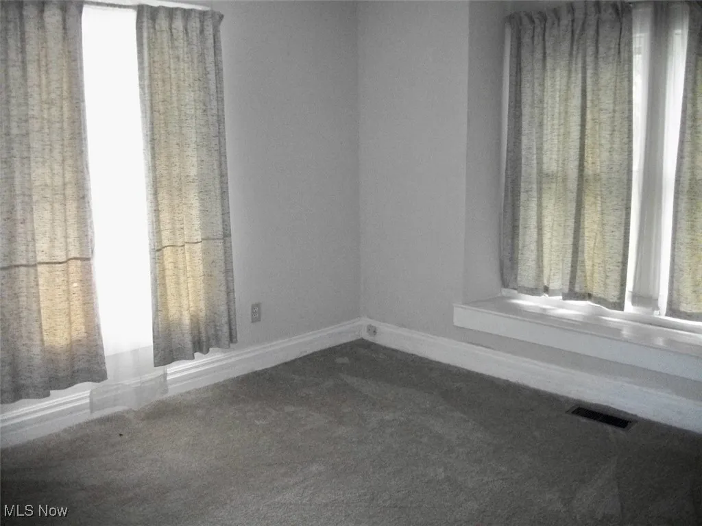Neutral Carpeted Living room featuring visible vents, baseboards, and a healthy amount of sunlight