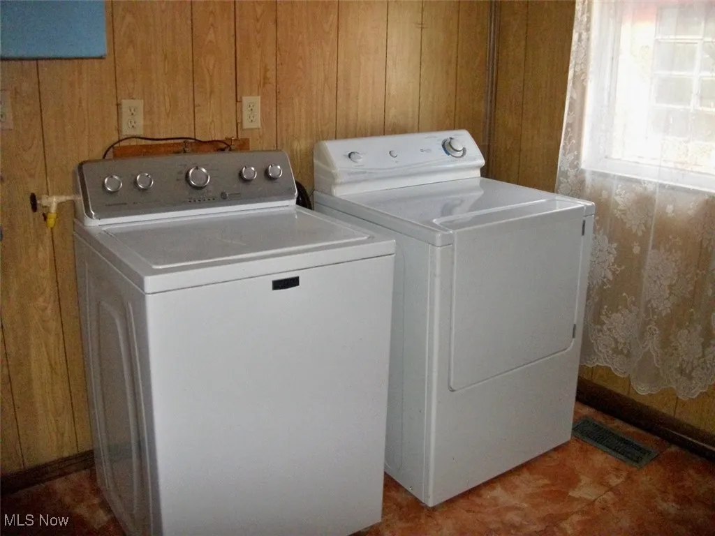 Laundry area with visible vents, wood walls, laundry area, and washing machine and dryer