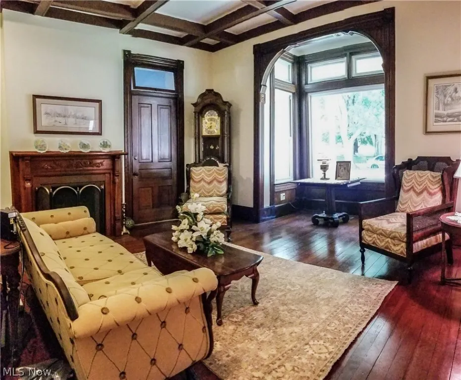 Living area with dark hardwood / wood-style flooring, beam ceiling, and coffered ceiling