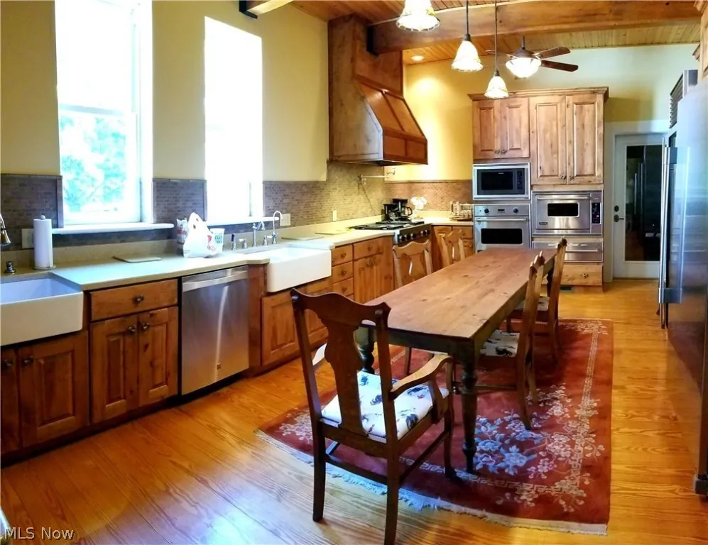 Kitchen featuring sink, beam ceiling, stainless steel appliances, and light hardwood / wood-style flooring
