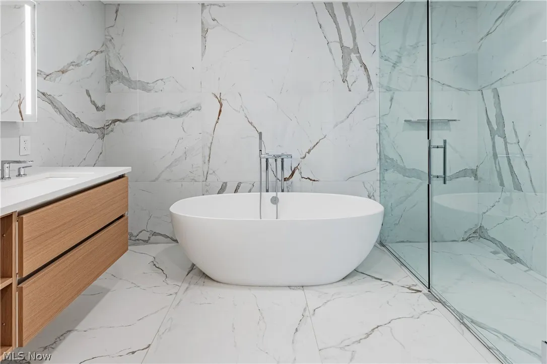 Bathroom with tile walls, tile flooring, and vanity