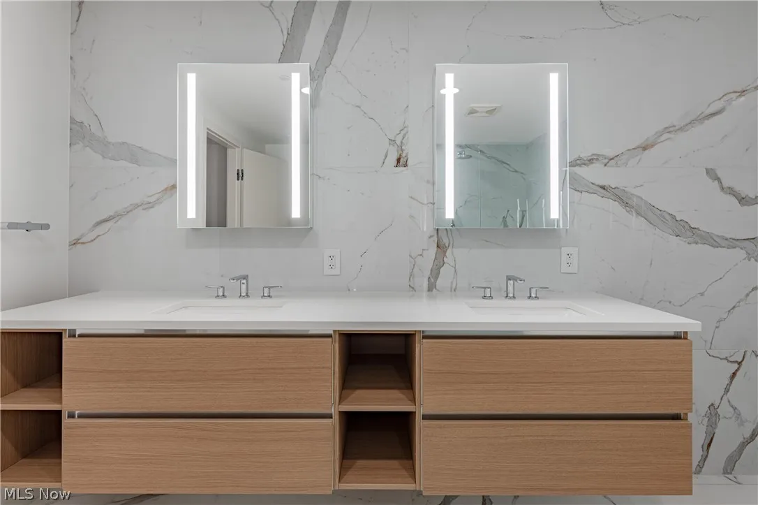 Bathroom featuring tile walls and dual bowl vanity