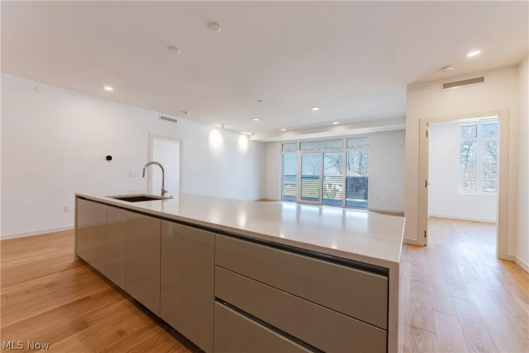 Kitchen featuring light hardwood / wood-style flooring, sink, a center island with sink, and gray cabinetry
