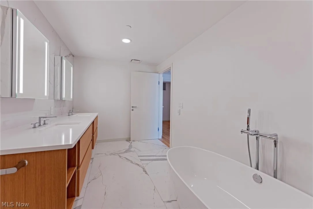 Bathroom with dual bowl vanity, tile floors, and a bath