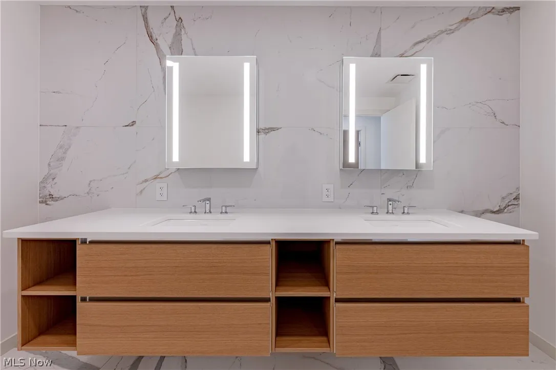 Bathroom with double sink vanity, tile walls, tasteful backsplash, and tile floors