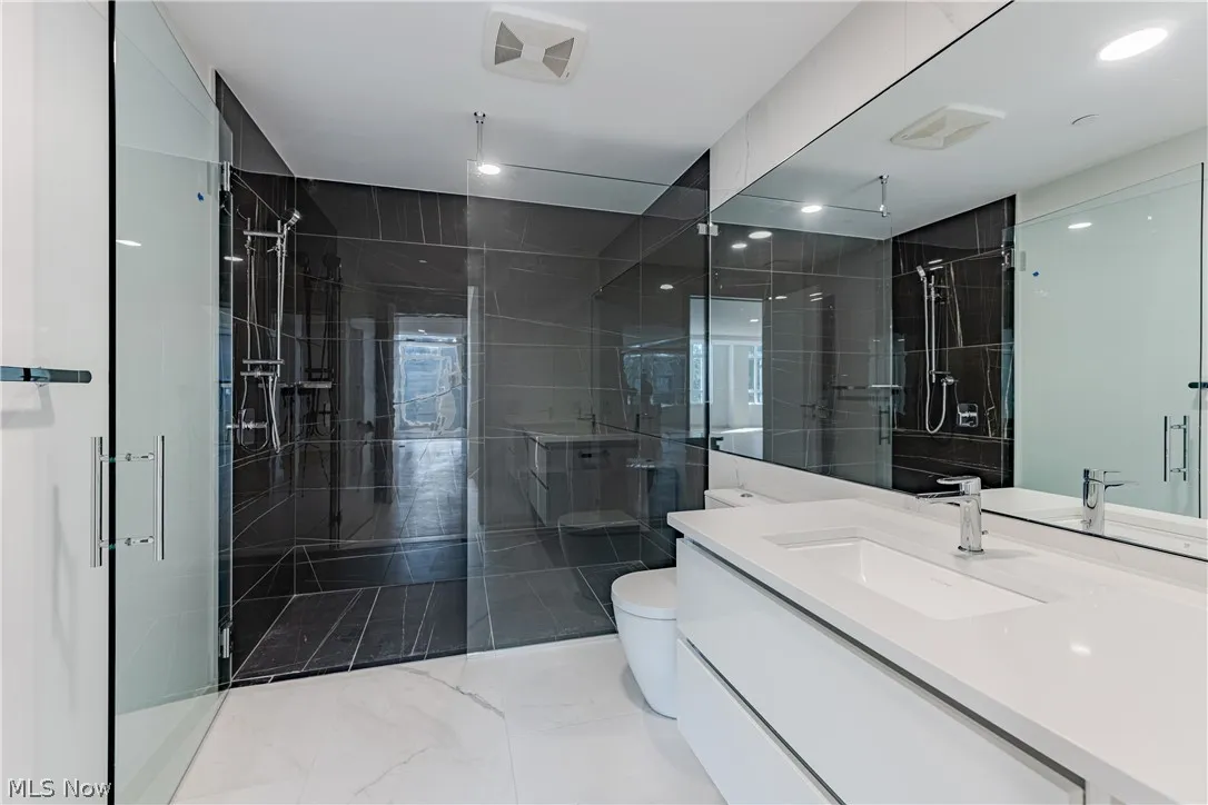 Bathroom featuring walk in shower, toilet, oversized vanity, and tile flooring