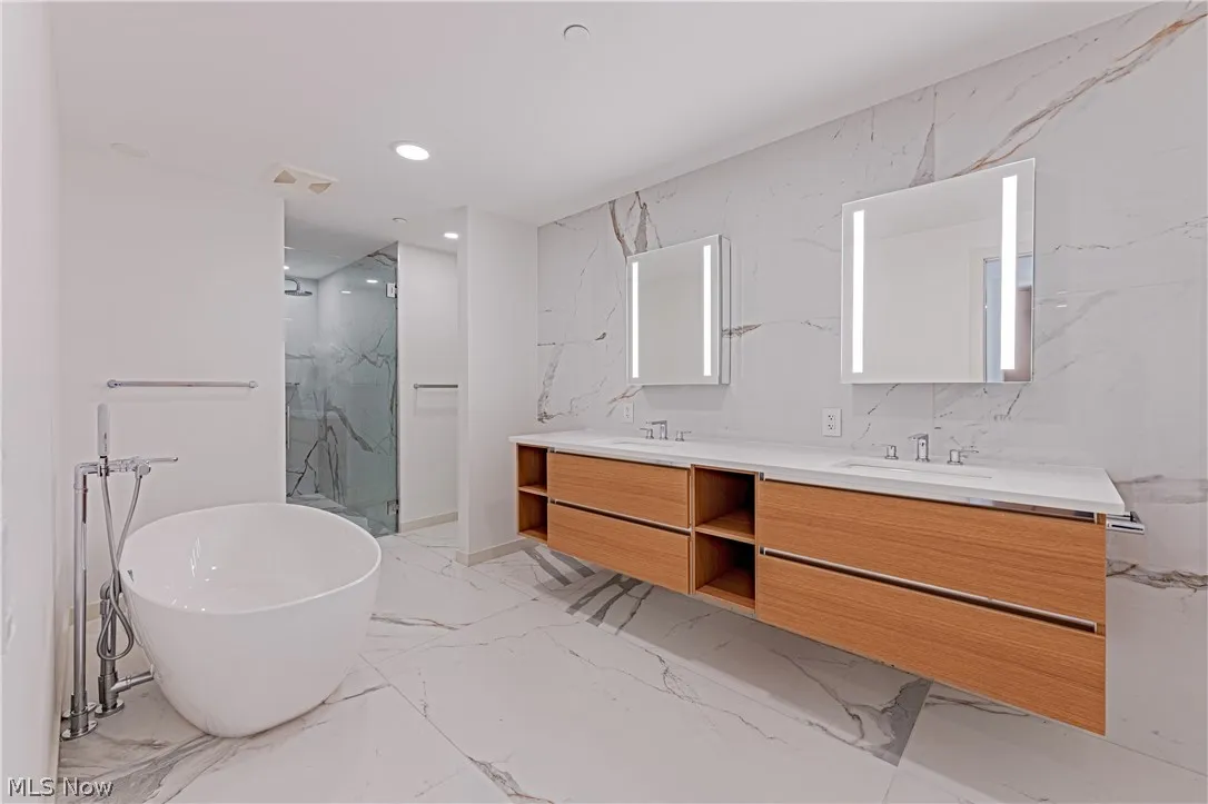 Bathroom with double sink, oversized vanity, tile flooring, and tile walls