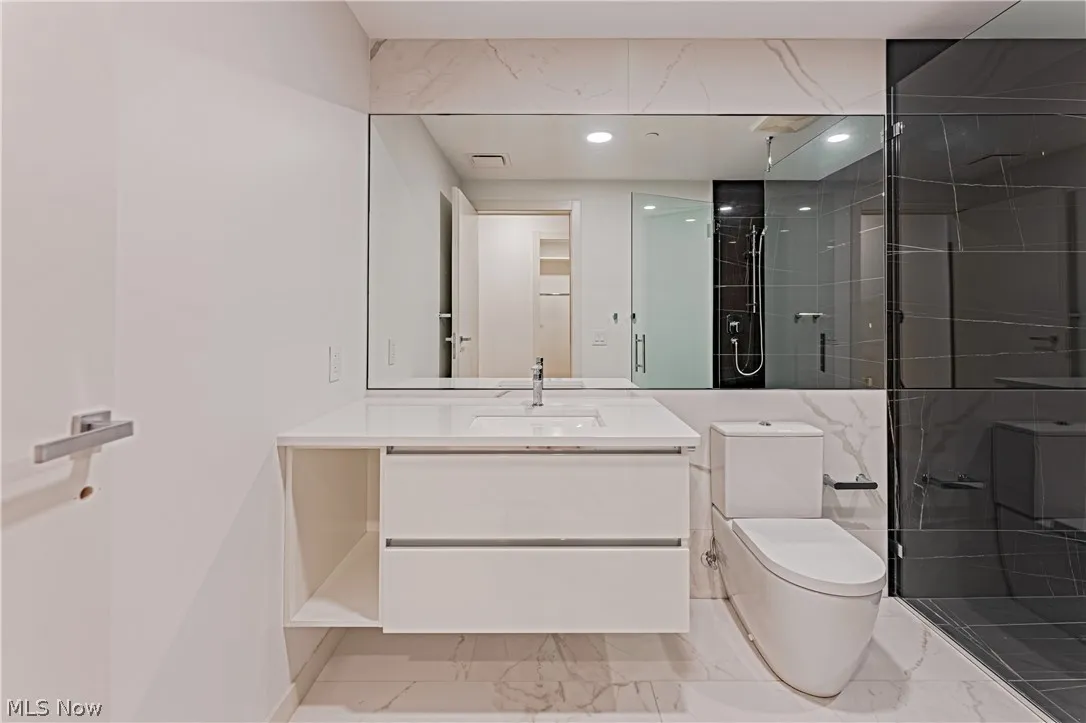 Bathroom with vanity with extensive cabinet space, a shower with shower door, tile floors, and toilet