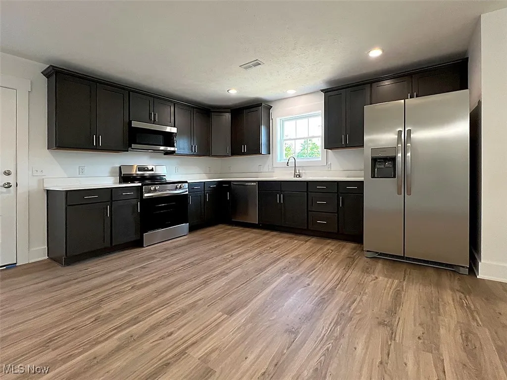 Kitchen with stainless steel appliances, light wood-style floors, light countertops, and recessed lighting