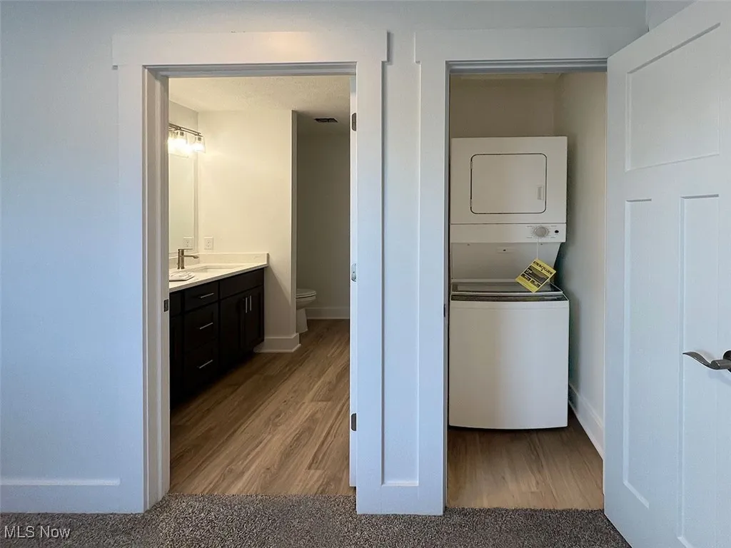 Washroom with stacked washer / drying machine and wood finished floors level 2