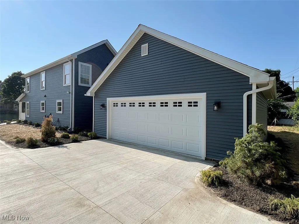 View of property exterior with concrete driveway and a garage