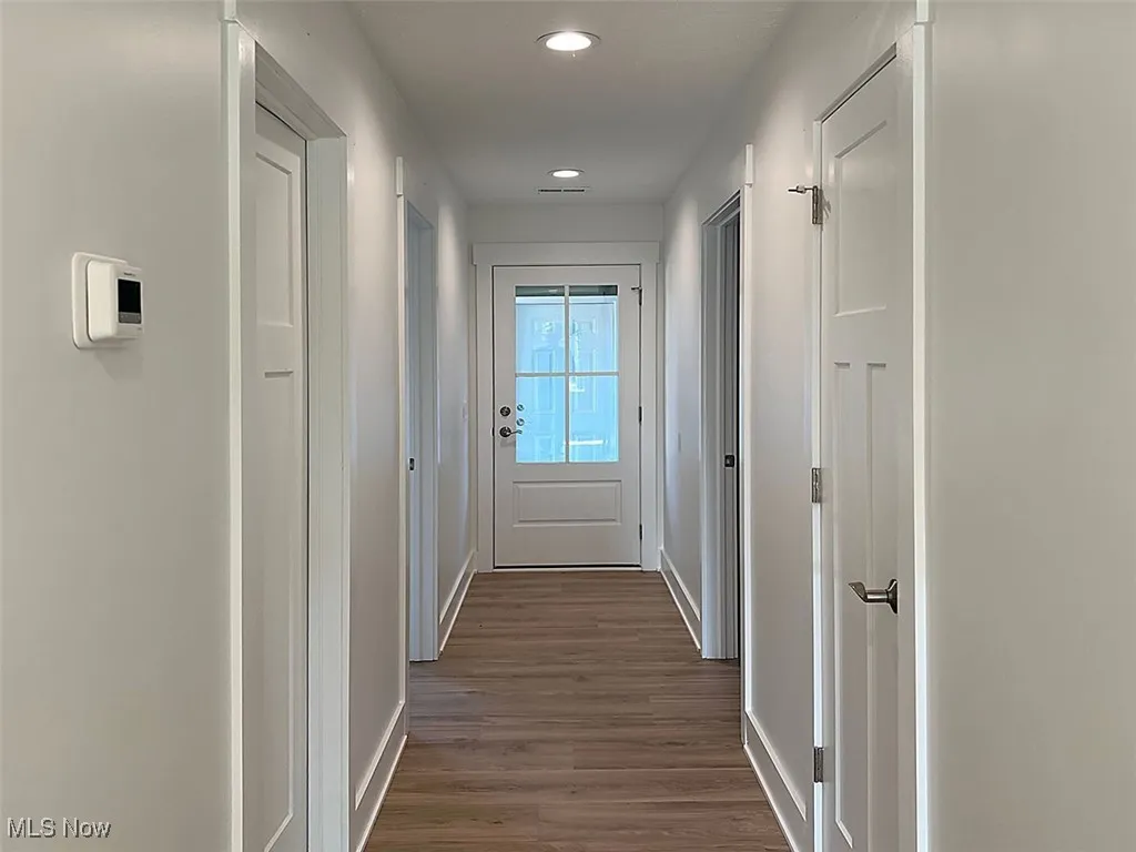 Hall featuring recessed lighting and dark wood-style flooring, door leading to attached garage