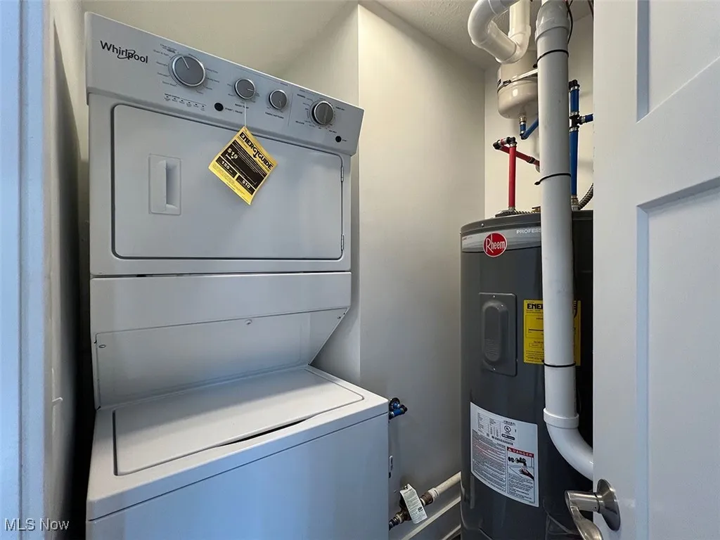 Laundry area featuring stacked washer and clothes dryer and electric water heater