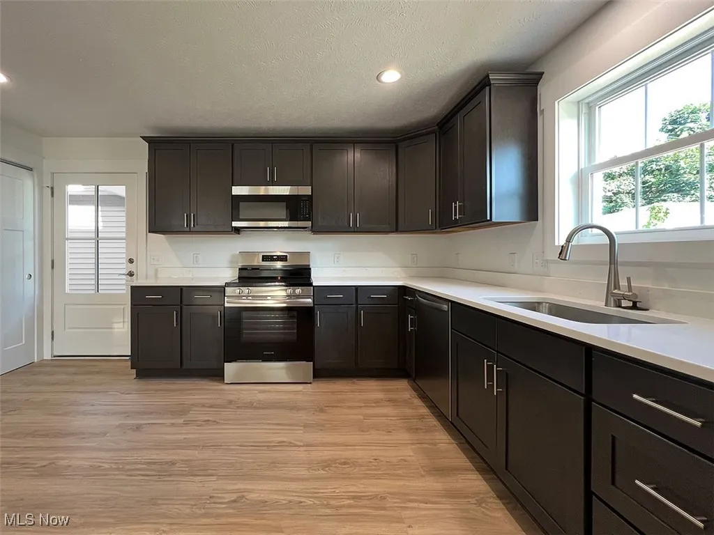 Kitchen featuring appliances with stainless steel finishes, light wood-style flooring, light countertops, recessed lighting, and a textured ceiling
