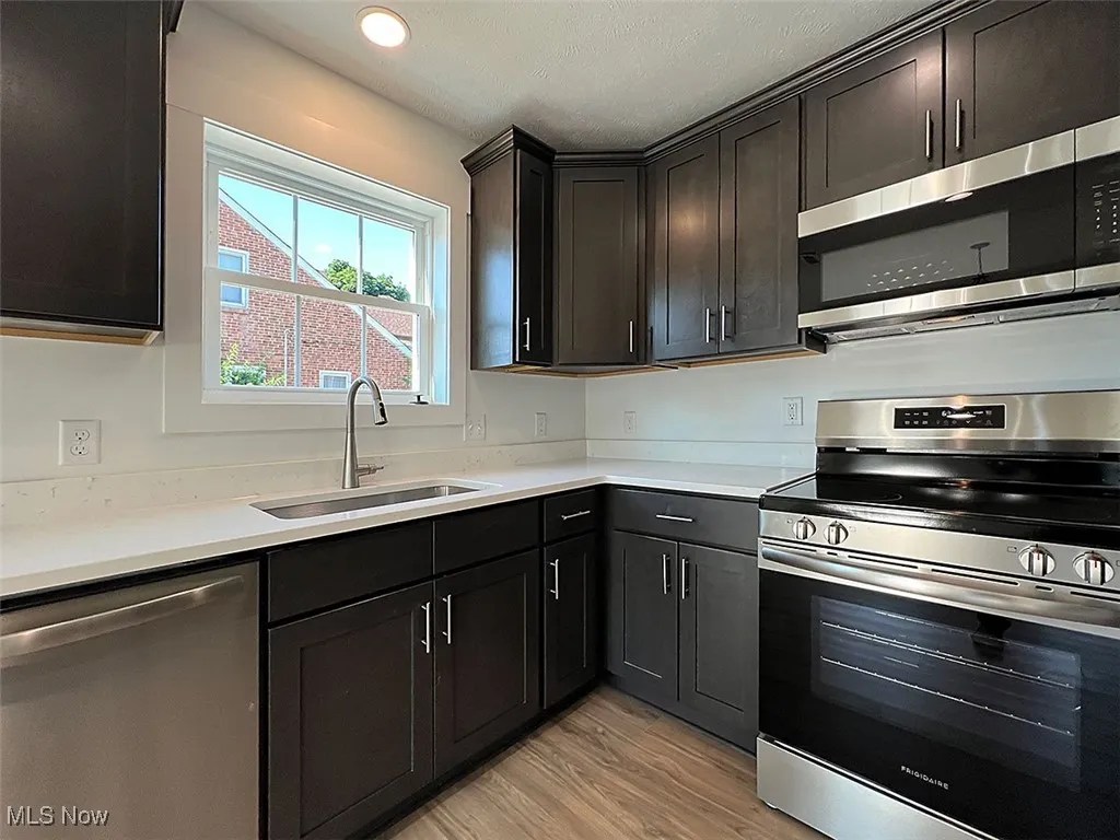Kitchen with appliances with stainless steel finishes, light wood-type flooring, light countertops, and recessed lighting