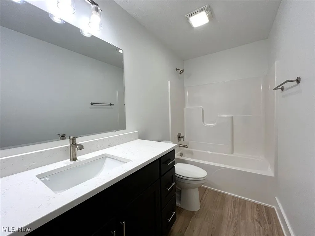 Bathroom featuring vanity, wood finished floors, and bathing tub / shower combination