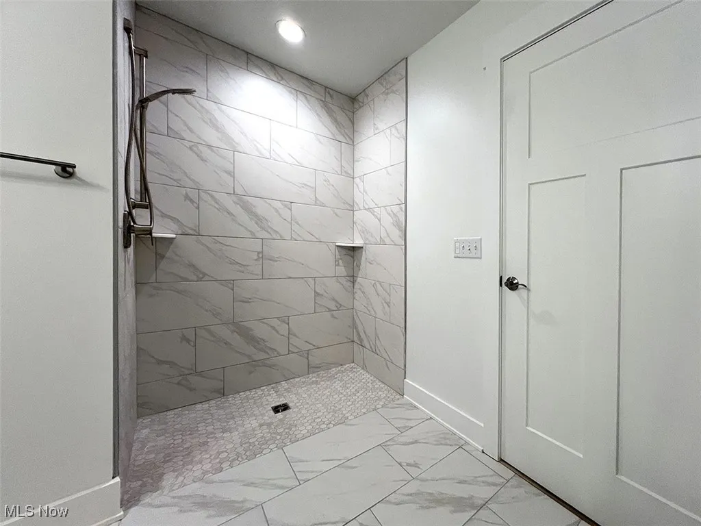 Master bathroom featuring marble look tiles, a tile shower, and recessed lighting