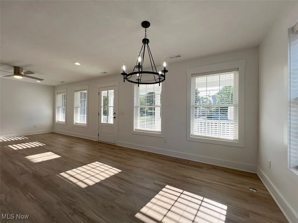 Dining area and great room with a chandelier, plenty of natural light, and wood finished floors